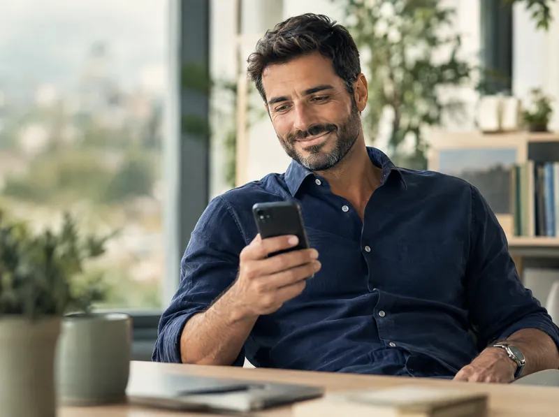 İş yerinde telefonuna bakıp gülümseyen baba.